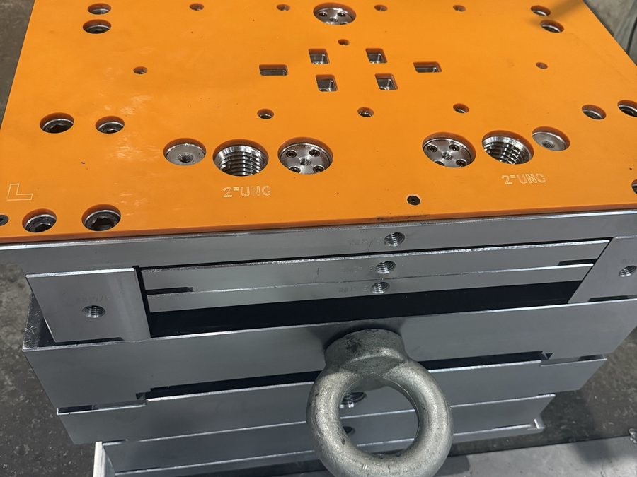 Large mold base hoisted by overhead crane in the workshop