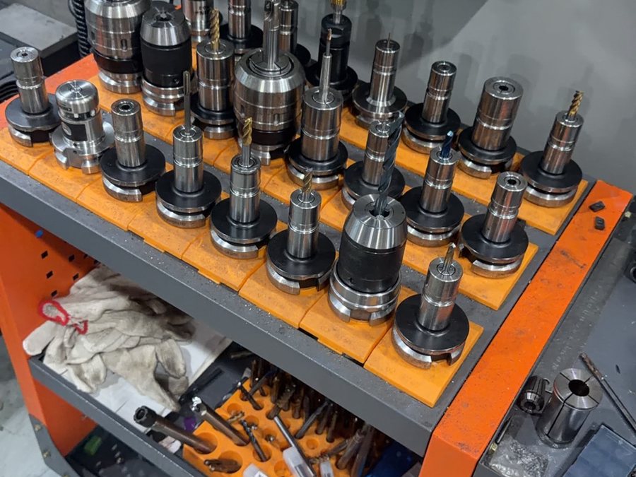 Tool holders and cutters loaded on a tool cart beside the machine