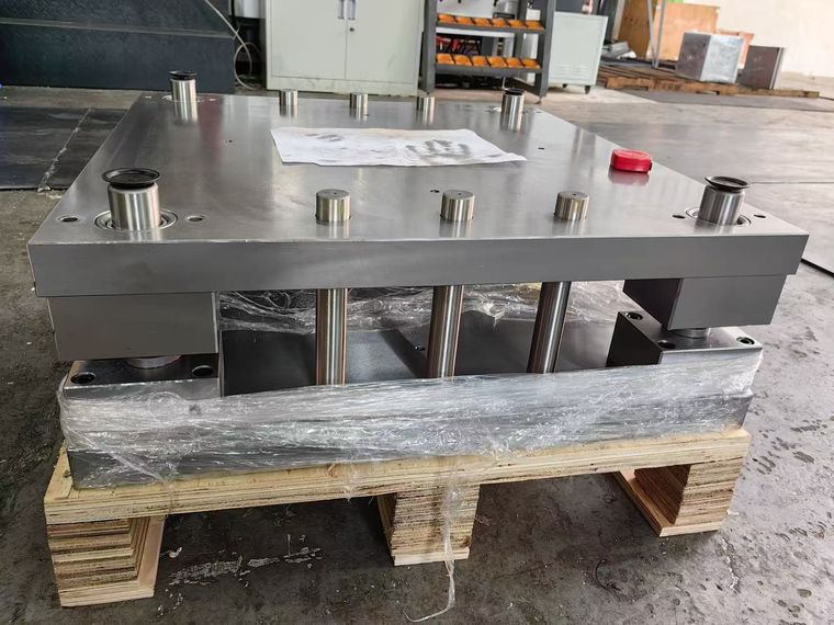 Standard plastic mold base resting on a wooden pallet in the workshop